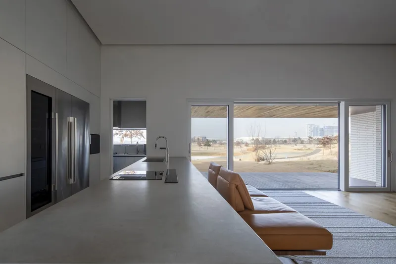 Kitchen island with integrated sink looking toward glass doors and bare trees in winter