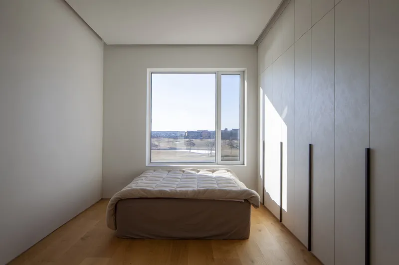 Compact bedroom with light oak flooring and built-in wardrobes catching afternoon sunlight