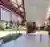 This architectural image showcases a modern pavilion structure within a park setting. The design fea