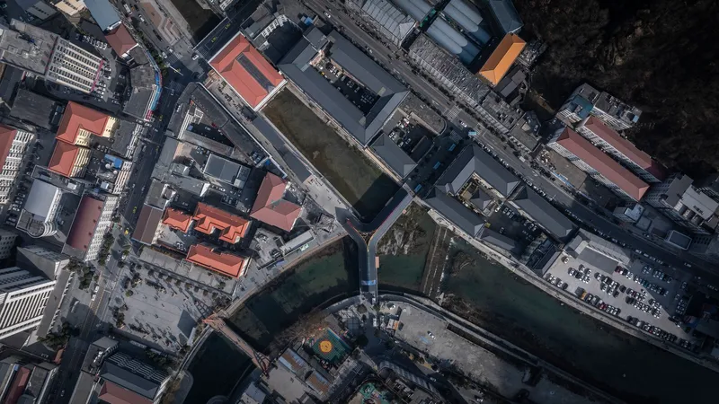 Aerial view of the pedestrian bridge crossing a river between dense urban blocks at dusk