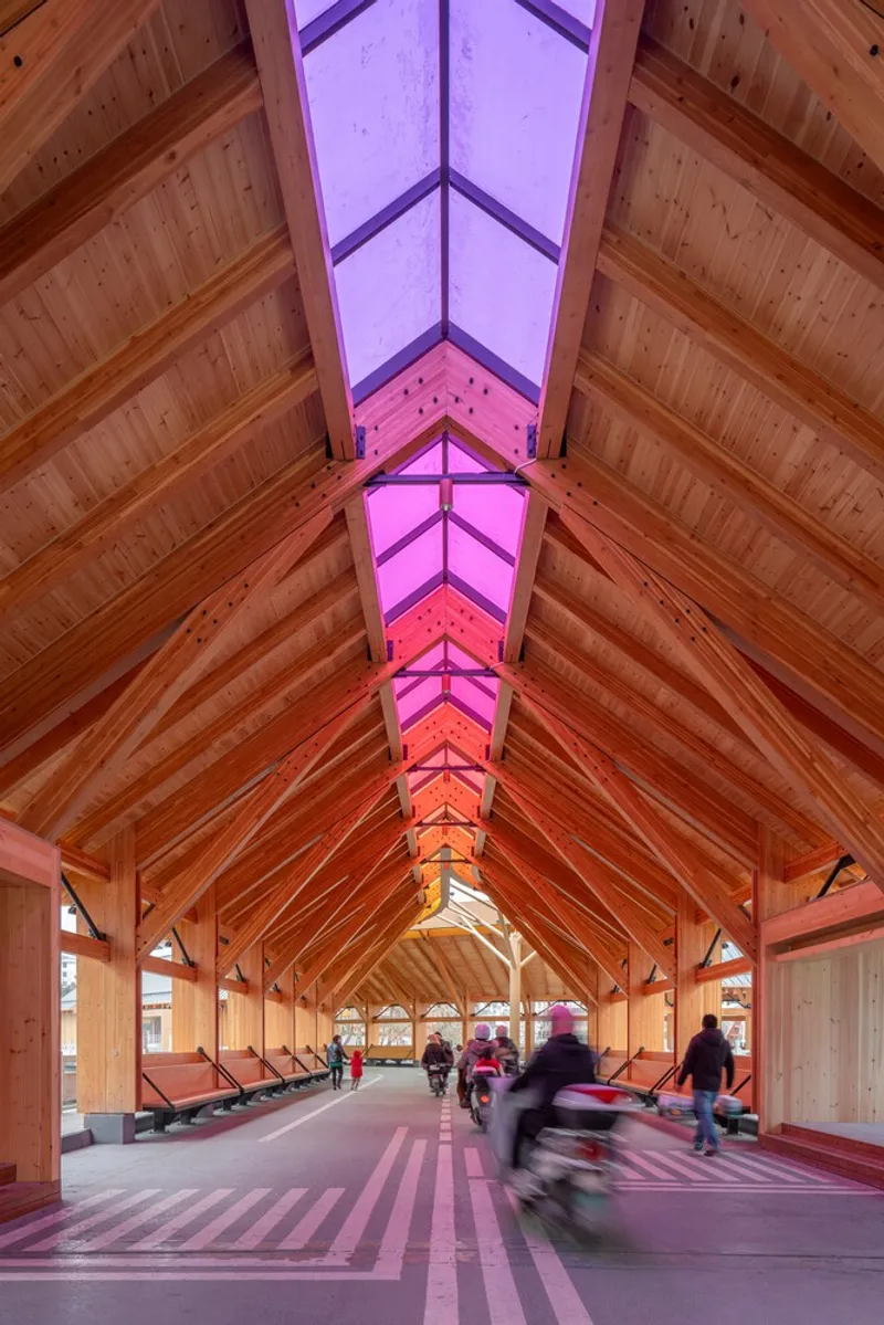 Upward view of the ridge skylight with purple and pink gradient glazing between timber rafters