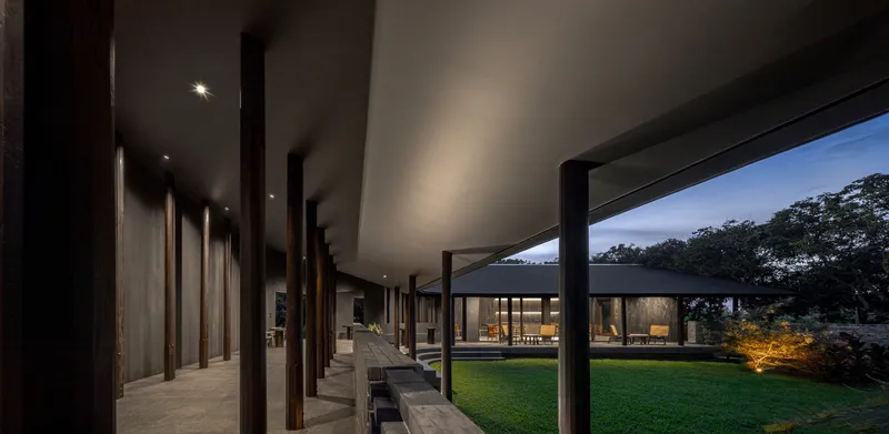 Evening shot of the same terrace with the lit cafe interior visible across the lawn
