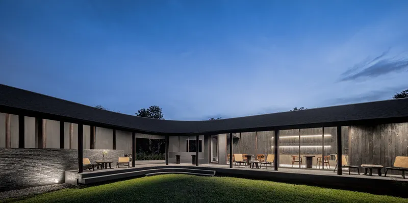 Dusk view across the central grass courtyard to the illuminated cafe dining room