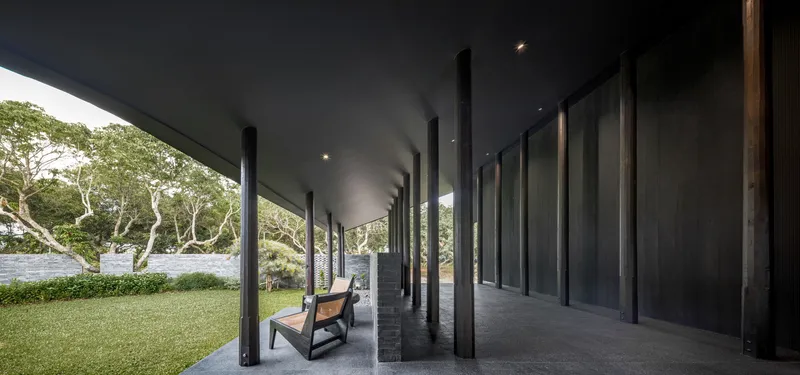 Covered terrace with timber chairs and views out to the garden and an existing tree