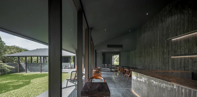Bar counter interior with dark timber walls and a view to the covered walkway outside