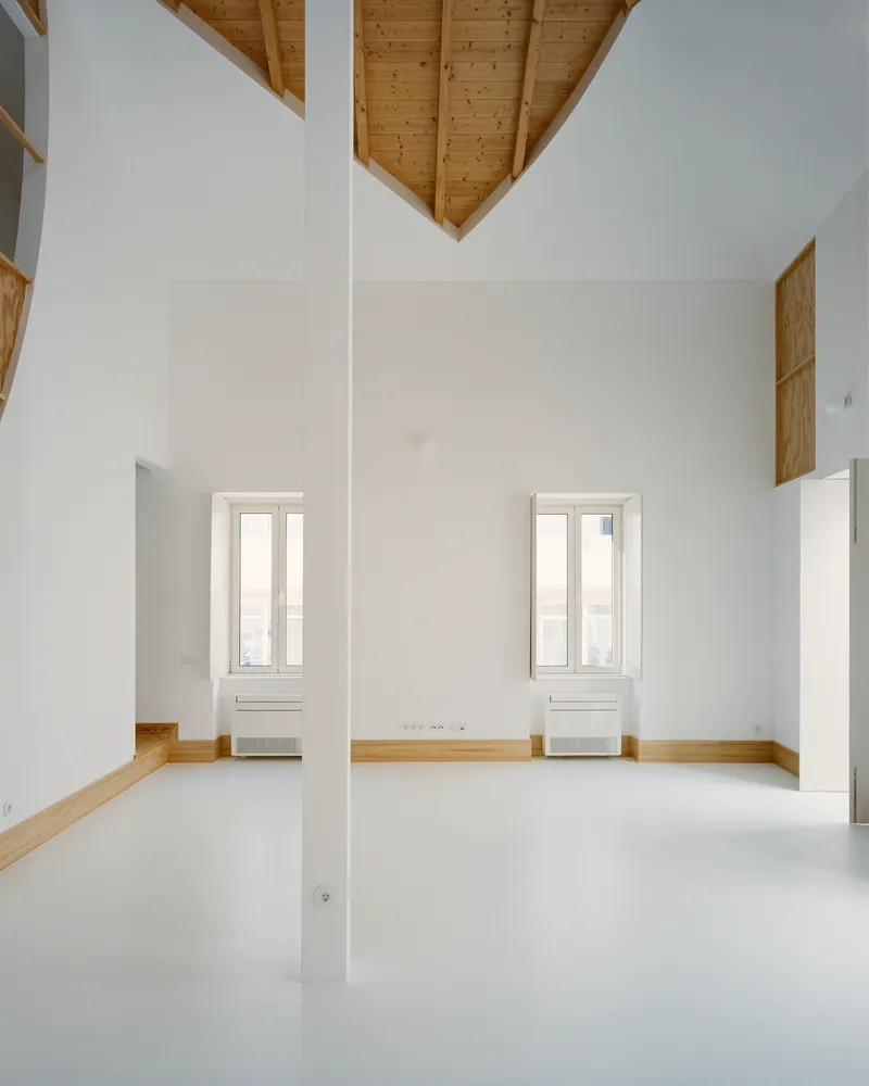 Living area with two original windows, the slim pillar and the cut-out wood ceiling above