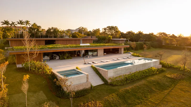 Sunset aerial view of the house and the lap pool set within the hillside garden