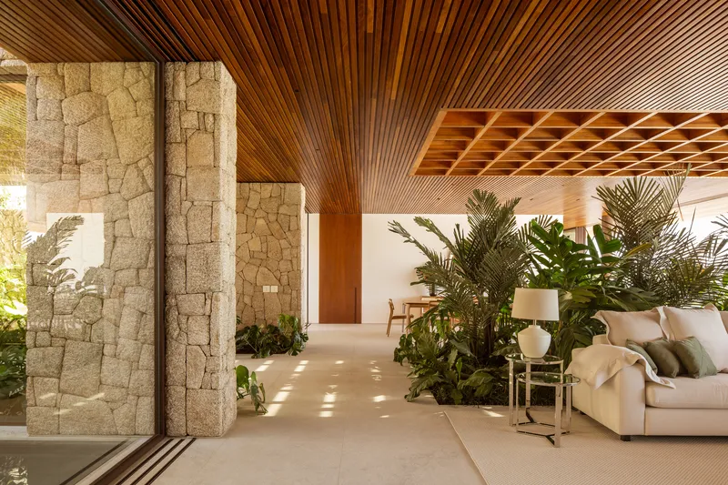 Living room with stone walls, a timber coffered ceiling and a large planted bed behind the sofa