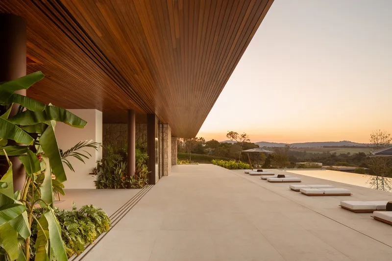 Covered veranda at sunset looking along the pool deck with lounge cushions and the timber slatted ceiling above